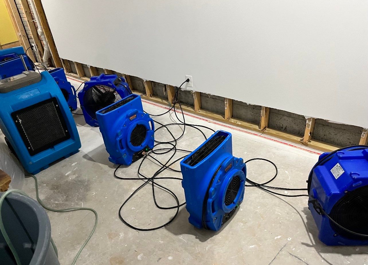 Mid-stage drying documentation showing dehumidification equipment and exposed ceiling framing during water restoration work.