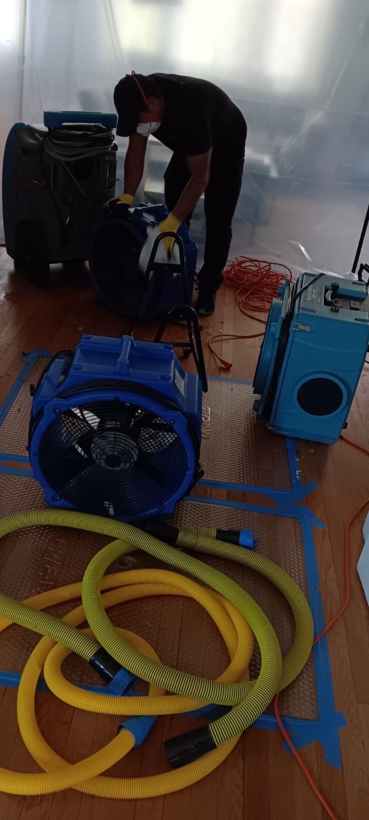 Drying process in progress with air movers and dehumidifiers working to reduce moisture levels in walls and flooring.