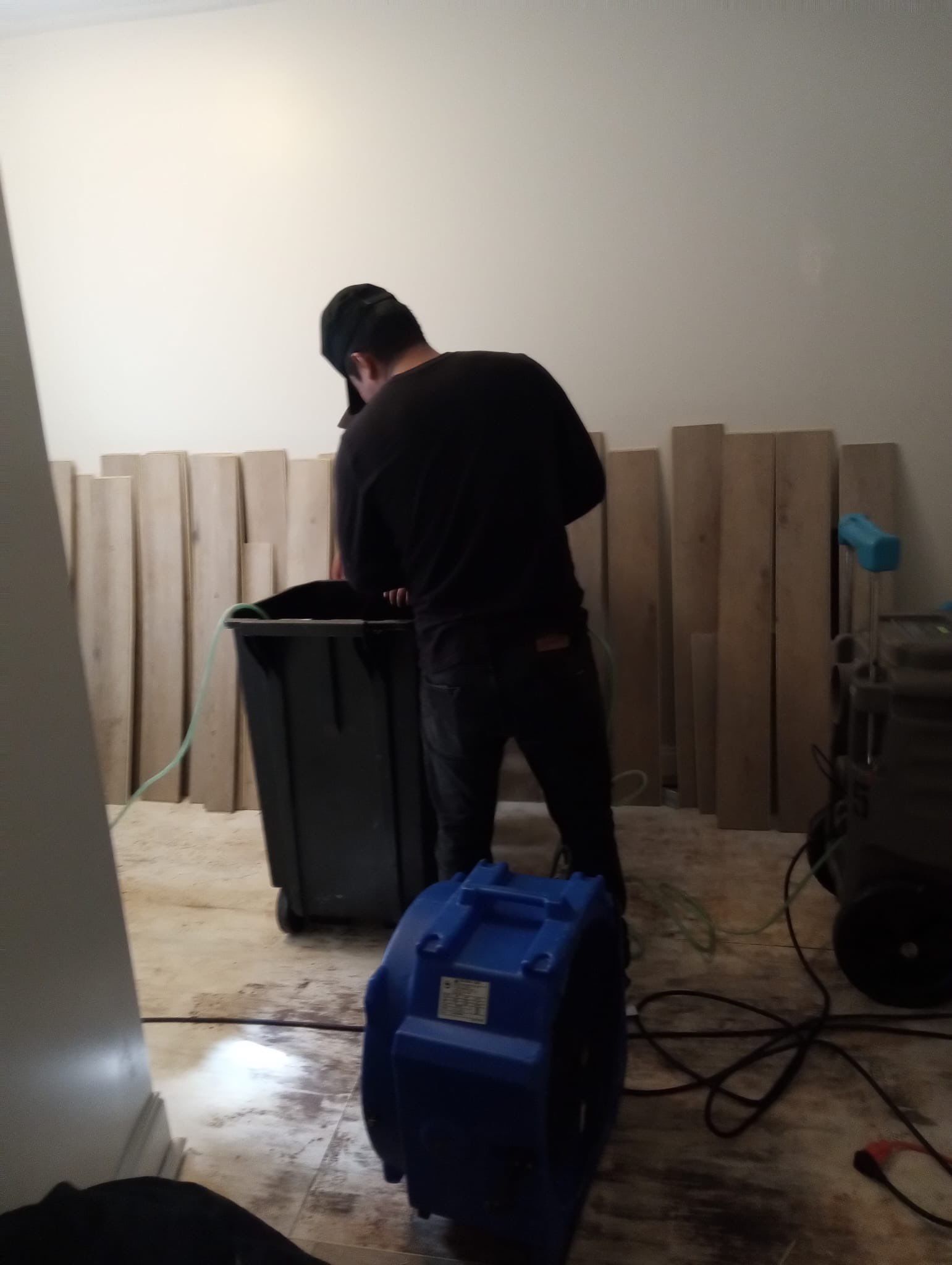 Standing water extraction underway in Washington water damage restoration, carpet removal in progress.