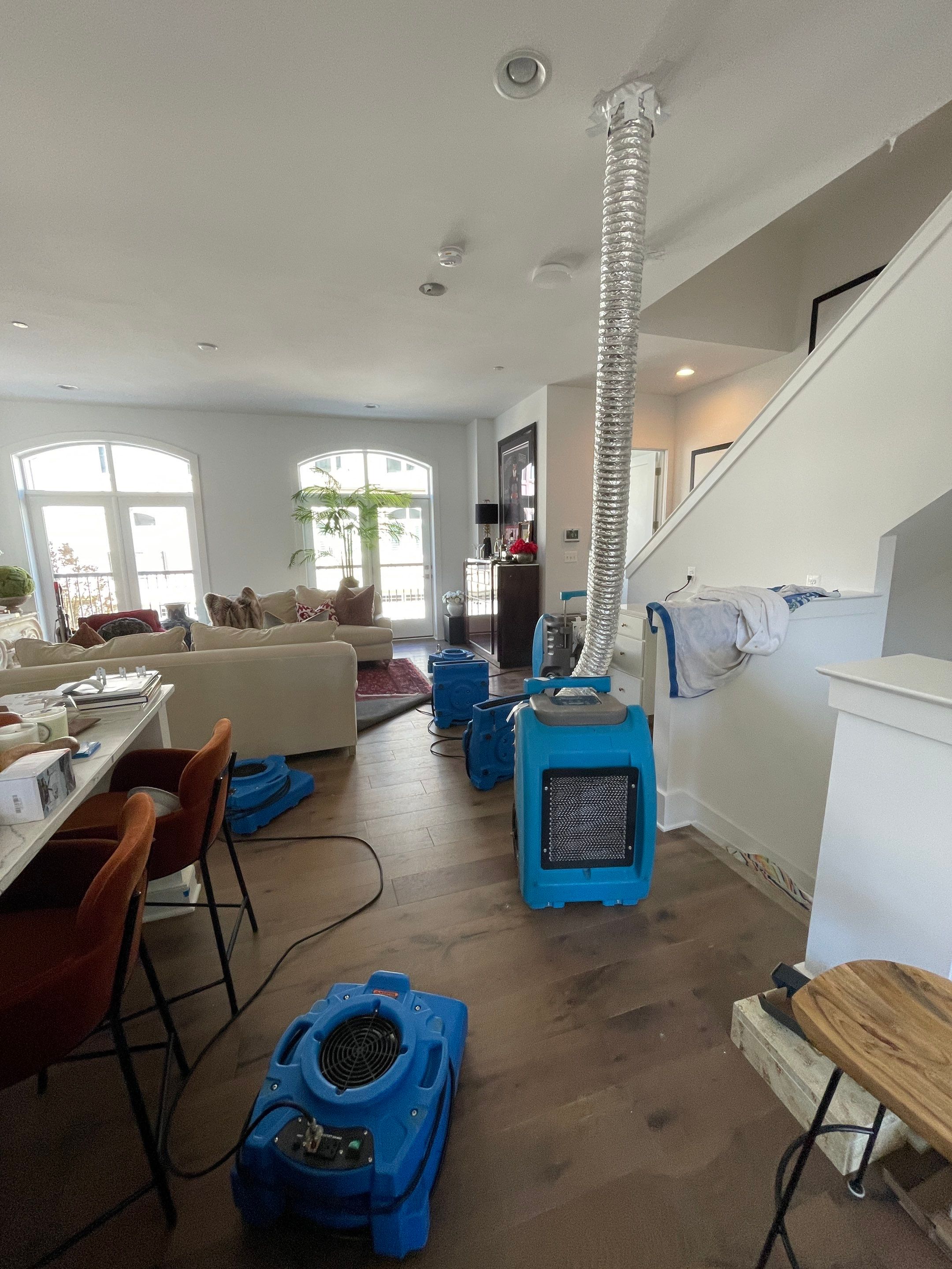 Structural drying phase with dehumidifiers and air movers deployed throughout affected interior space.