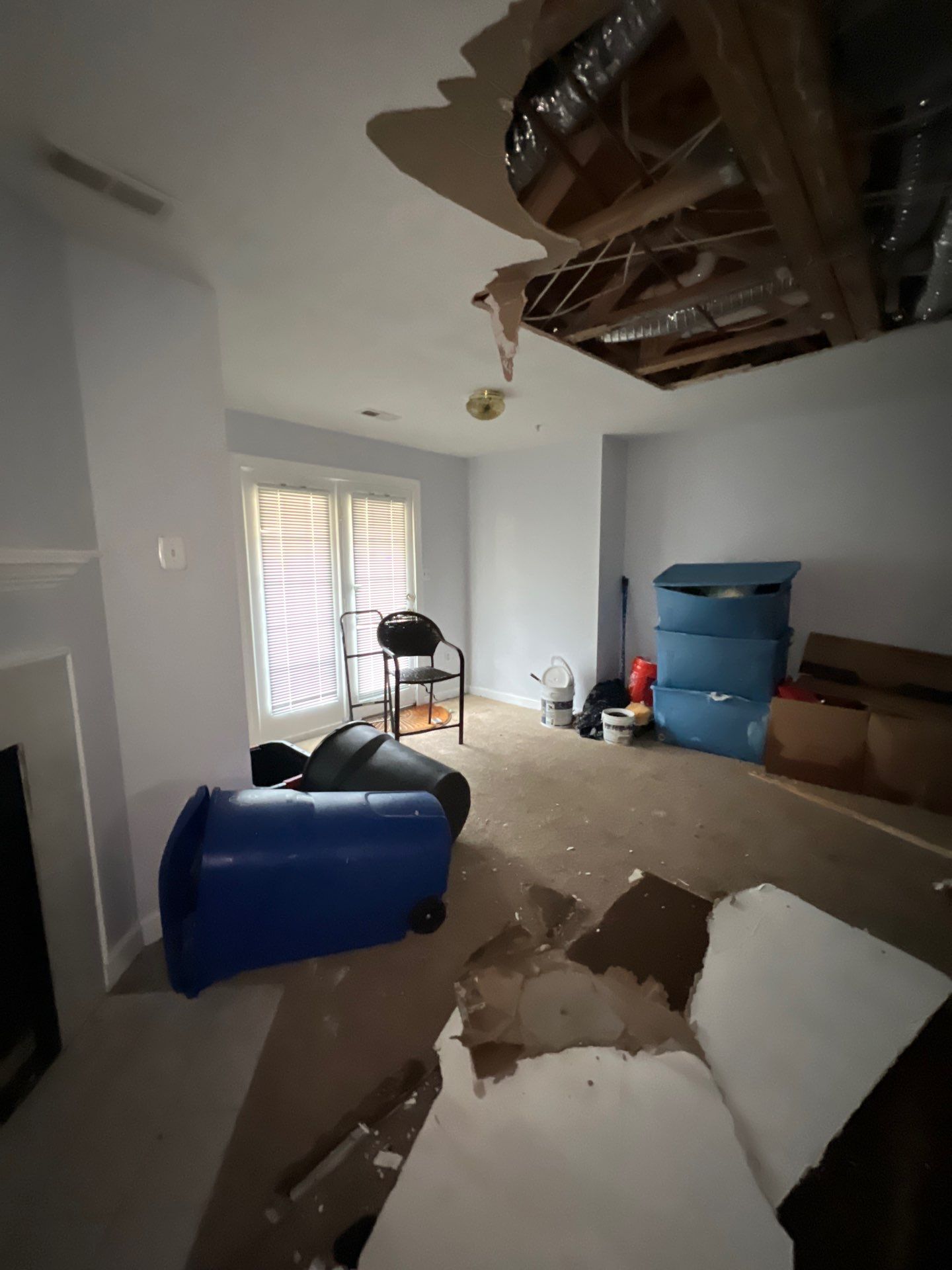 Exposed ceiling cavity with structural framing visible after water-damaged drywall extraction.