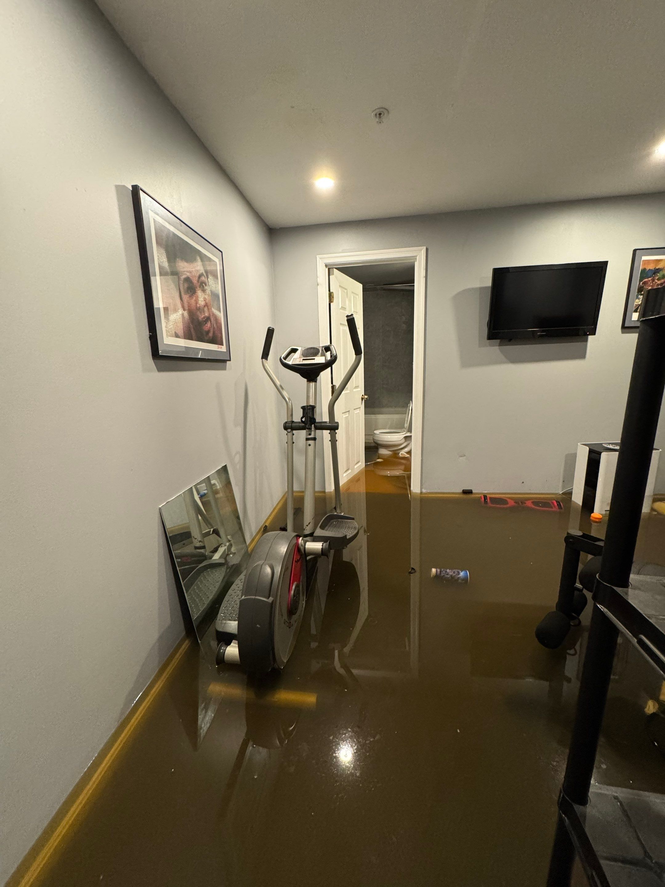 Standing water extraction underway in Marlboro home, technician positioning submersible pump.