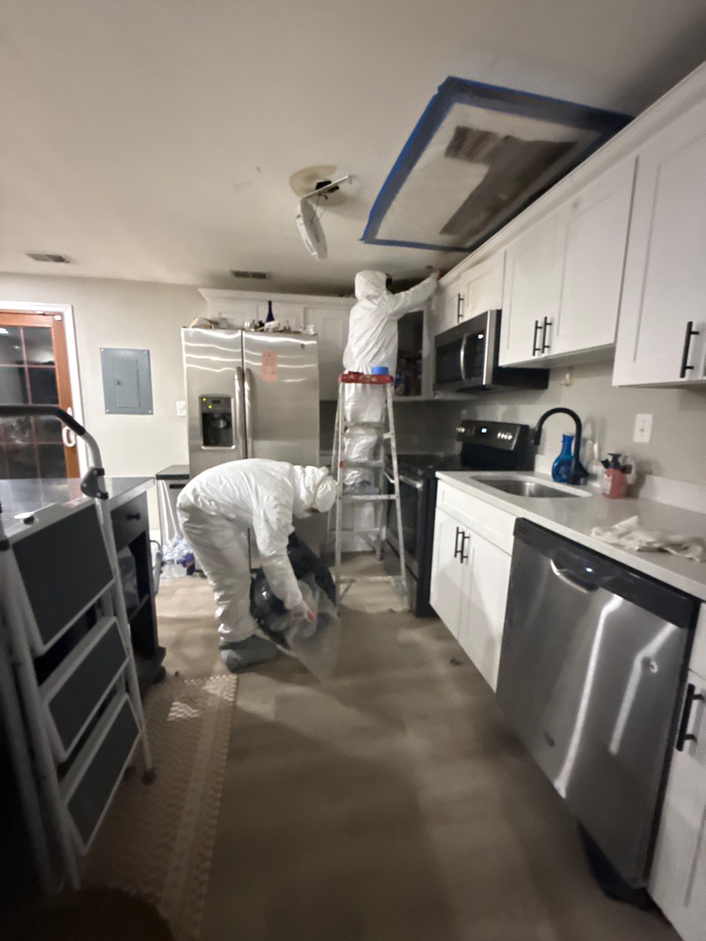 Dehumidifier and air movers working to extract moisture from wall and ceiling assembly.