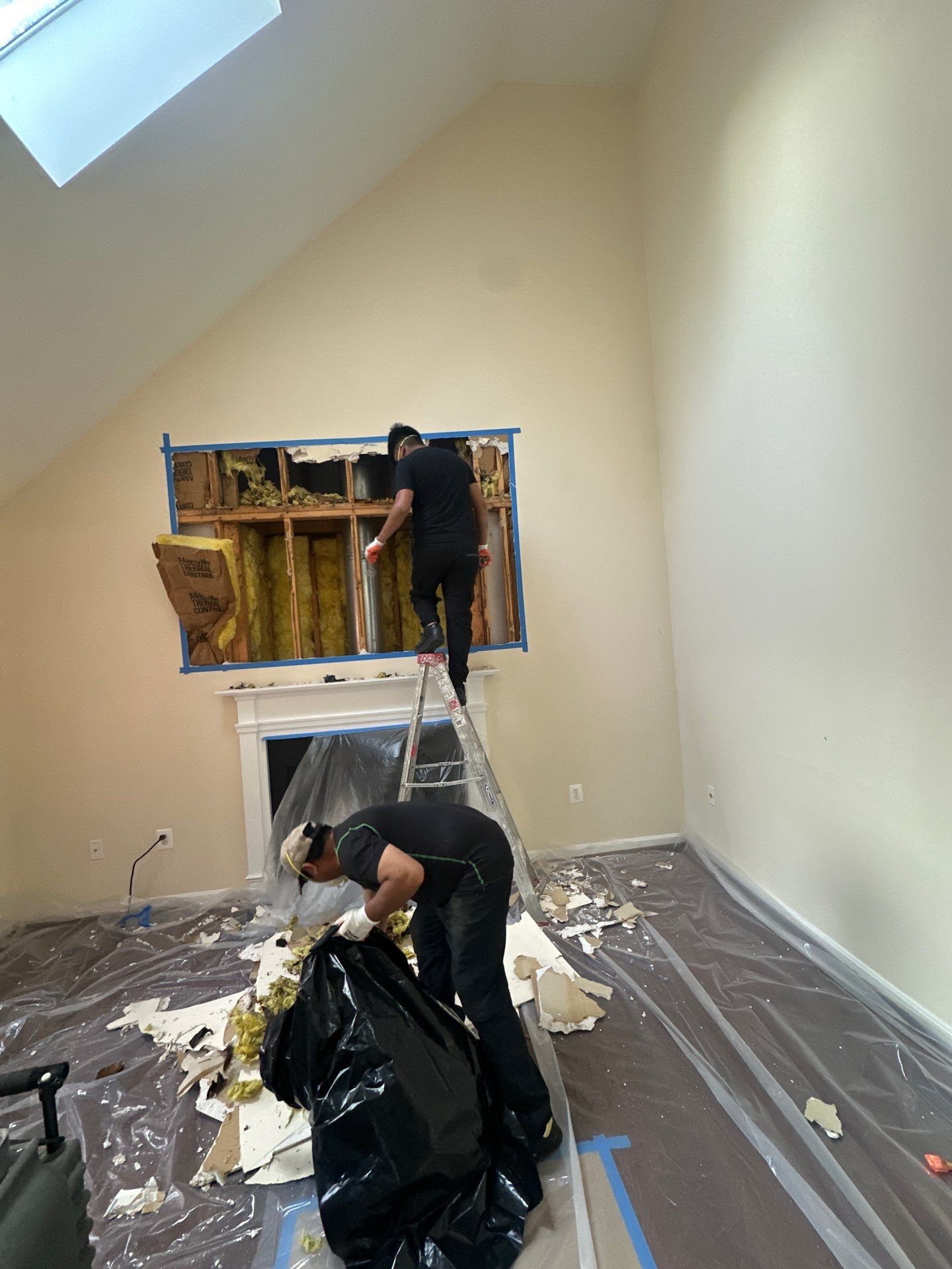 Drywall removal exposes mold-affected framing and insulation in mold remediation containment area.