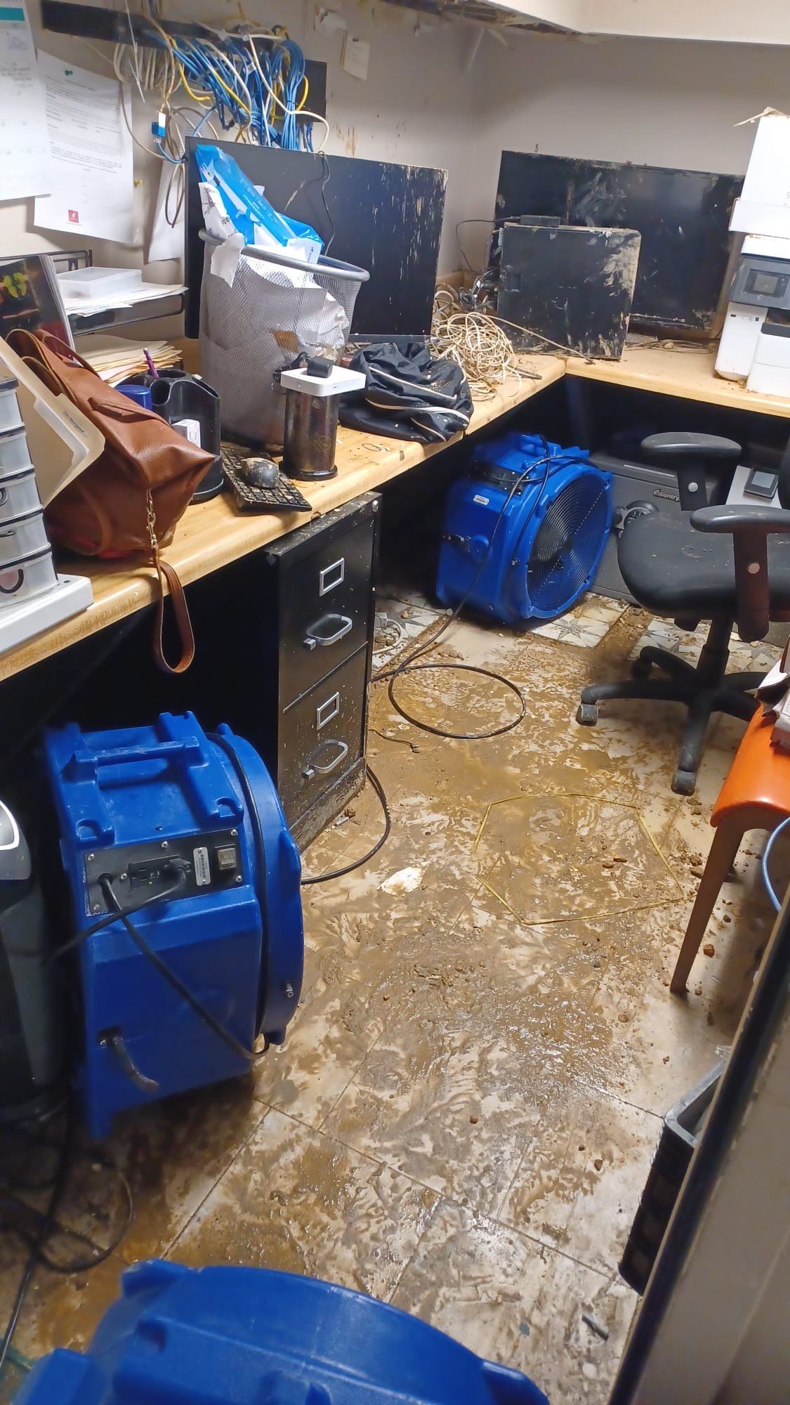Standing water extraction underway in Washington water damage restoration, wet flooring visible.
