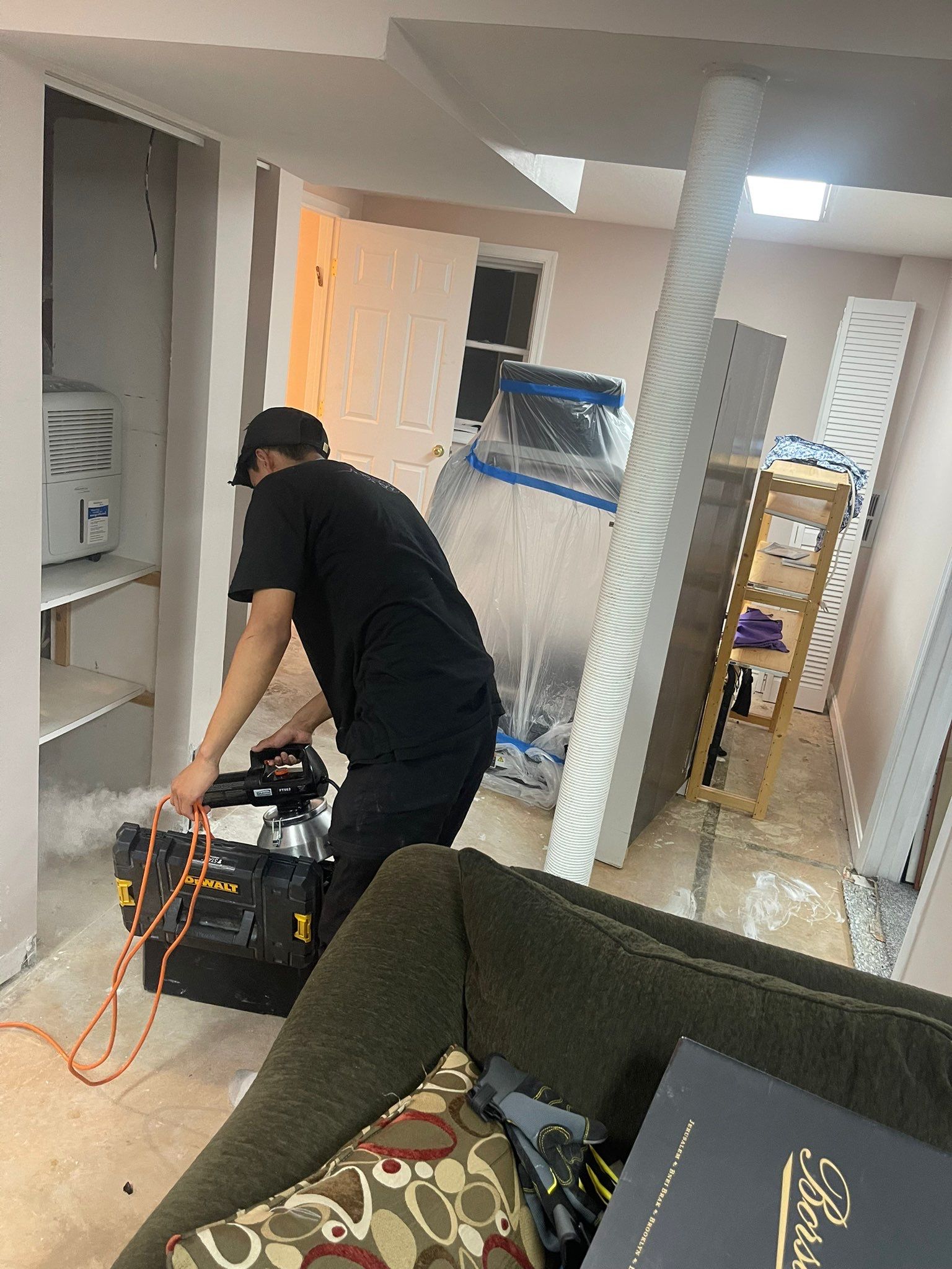 Standing water extraction underway in Potomac water damage restoration, wet carpet and flooring visible.